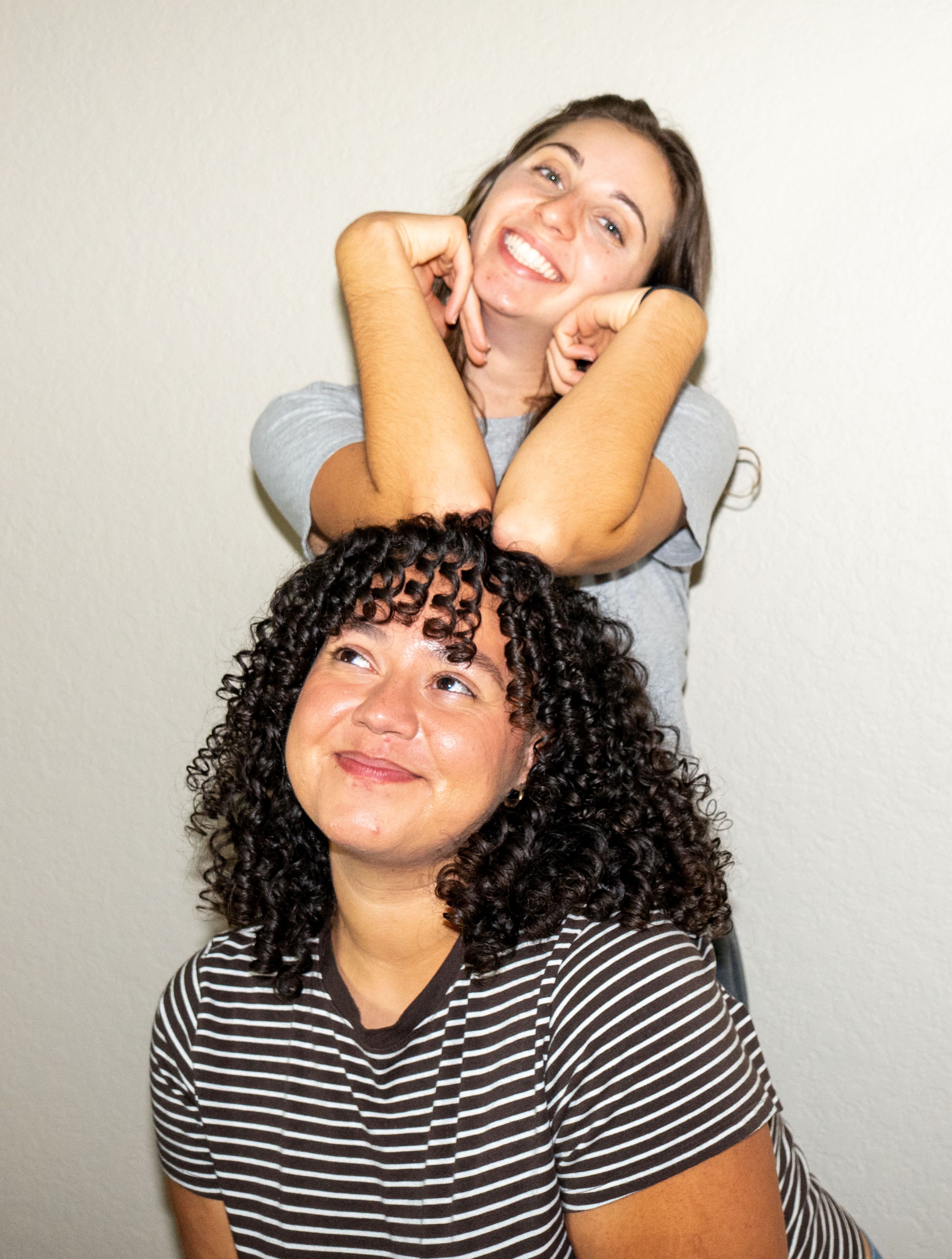 Two friends laughing on a white backdrop